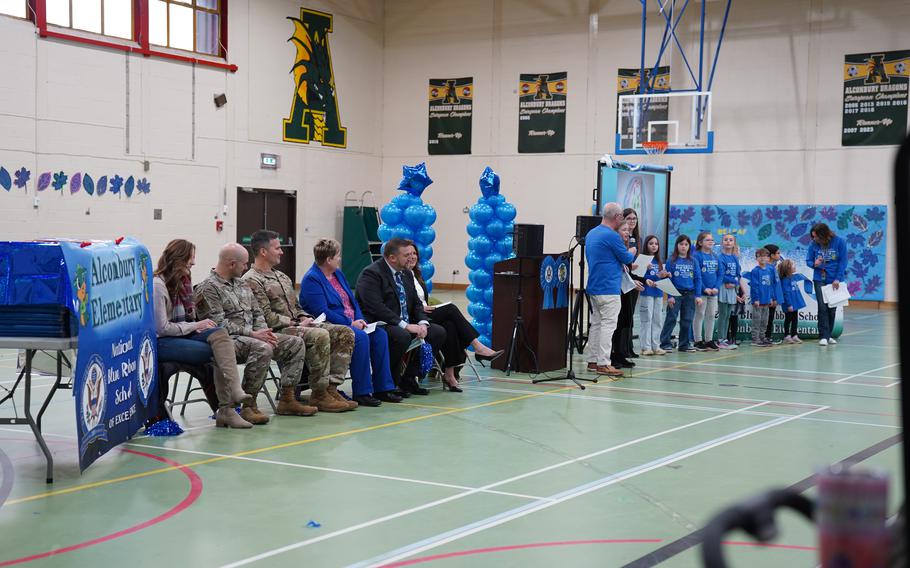 A handful of students line up to speak on the right, while a few guests sit and listen on the left.