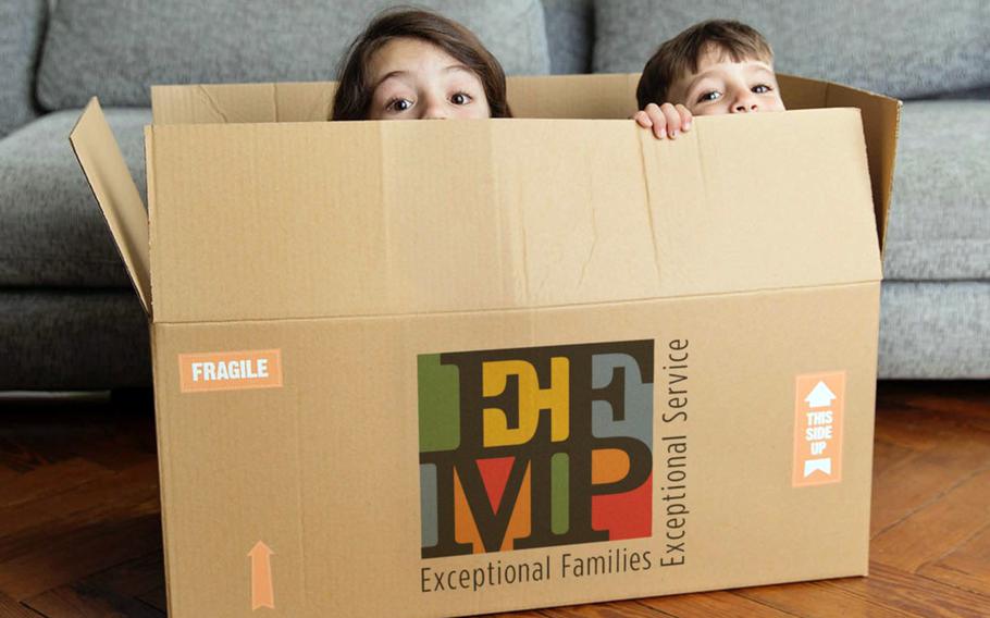 Two children sit in a cardboard box and peak over the edge.