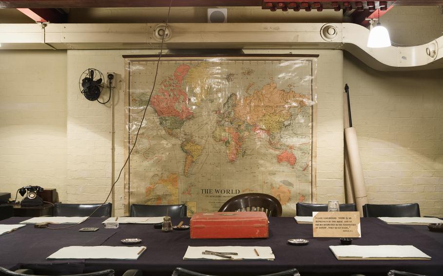 A long wooden desk with papers and a map in the background.