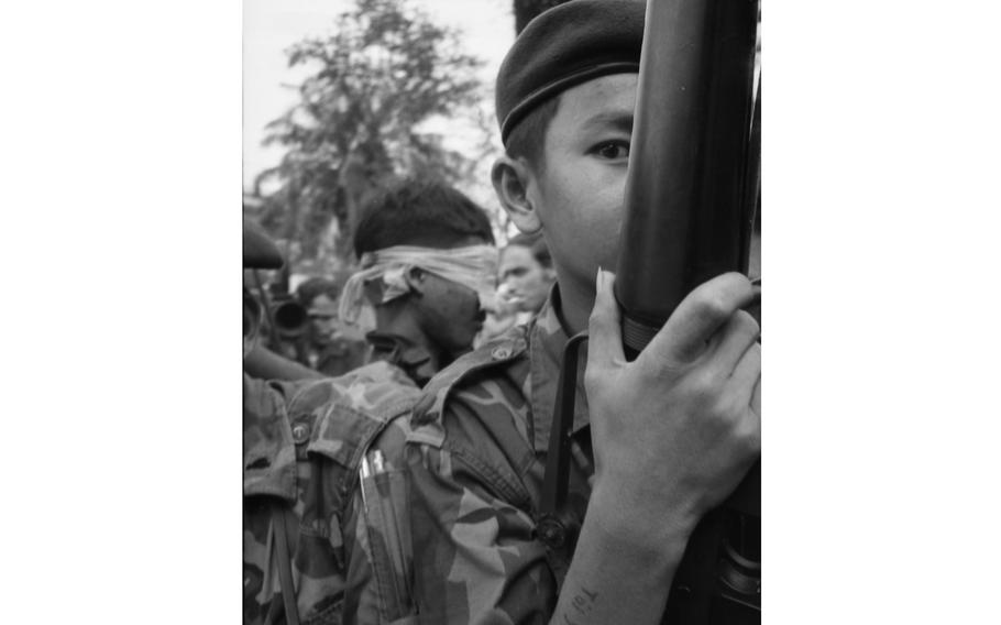 Army of the Republic of Vietnam soldiers guard a captured and blindfolded Viet Cong fighter in a jeep.