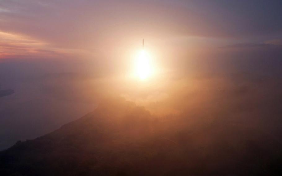 An intercontinental ballistic missile, seen from a distance, rises into the sky.