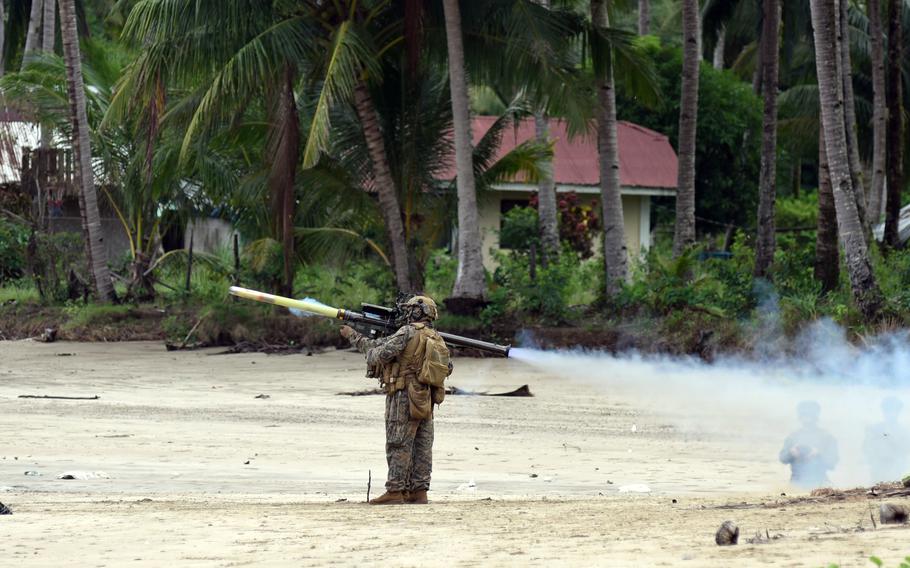 A Marine fires a missile launcher from a beach.