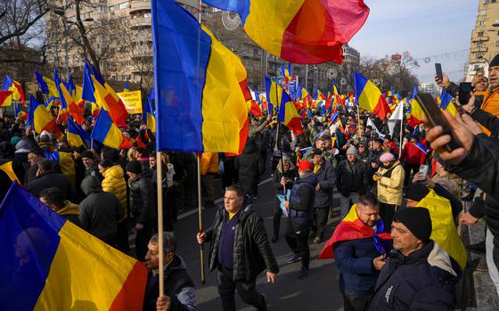 Protesters walk holding Romanian flags during a rally organized by the right wing Alliance for the Unity of Romanians (AUR), calling for free elections after Romania' s Constitutional Court annulled the first round of presidential elections last December, in Bucharest, Romania, Sunday, Jan. 12, 2025. (AP Photo/Vadim Ghirda)