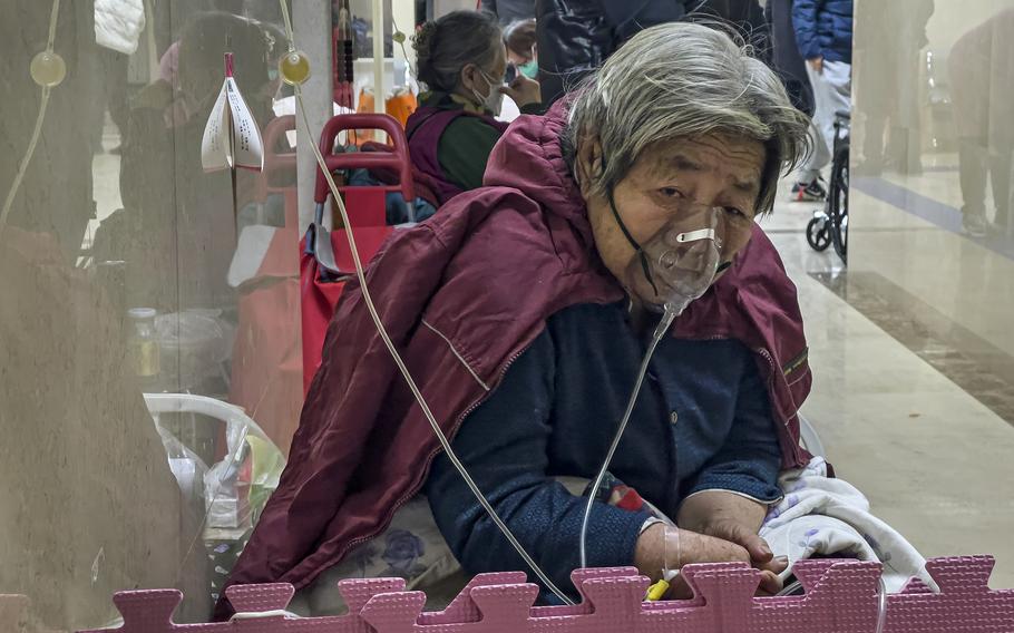 An elderly patient receives an intravenous drip while using a ventilator