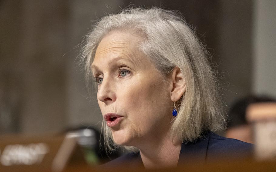 A woman wearing a suit speaks into a microphone.