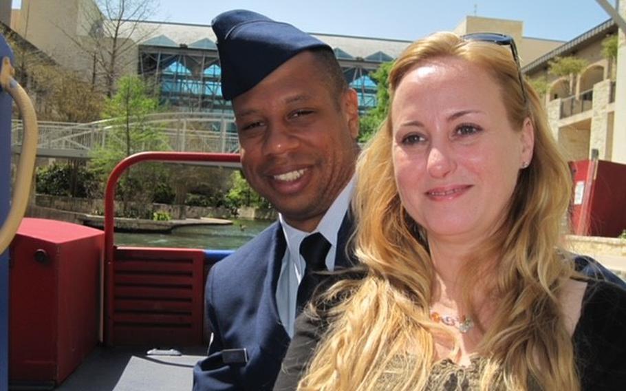 A man in uniform on the left next to a woman as they pose for a photo.