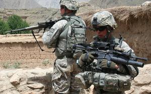 Two soldiers with rifles in a mountainous area.