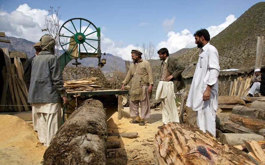 Afghan men prepare to cut logs into lumber