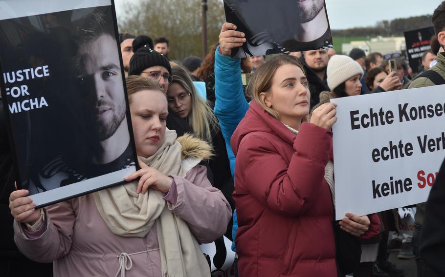 People hold signs as they protest outside a U.S. Air Force base in Germany.