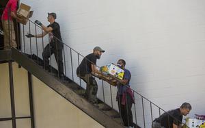 Members of American Legion Post 37 in Norfolk pass food boxes down a stairway at the side of their building Saturday morning, Oct. 26, 2024, in preparation of their monthly food giveaway to veterans and their families. (Bill Tiernan/ For The Virginian-Pilot)