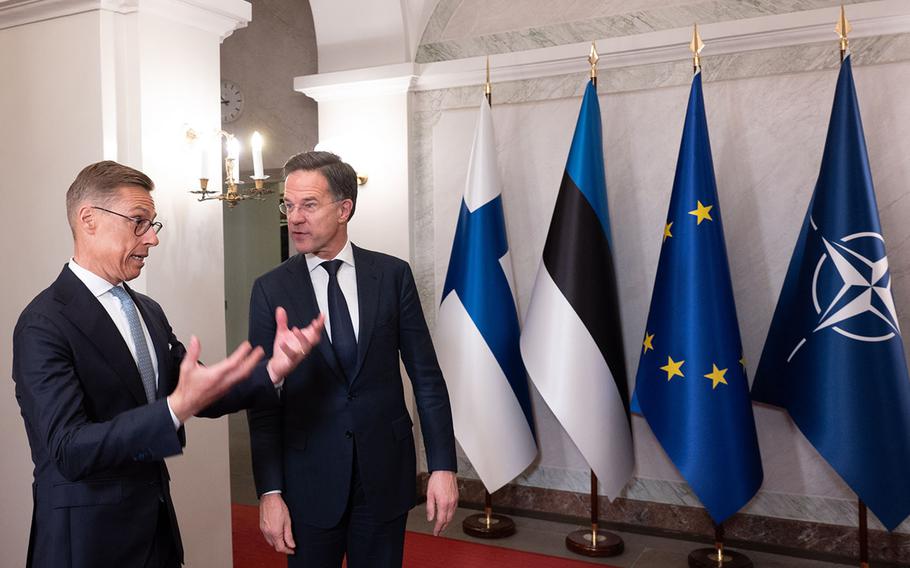 Mark Rutte and Alexander Stubb talk to each other in front of flags.