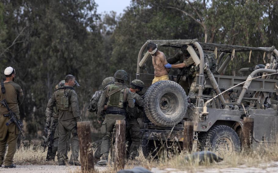 Israeli soldiers handle a blindfolded Palestinian detainee from Gaza after arriving to the Israeli side of the border on Wednesday. The detainee's hands were tied behind his back with a plastic zip tie.