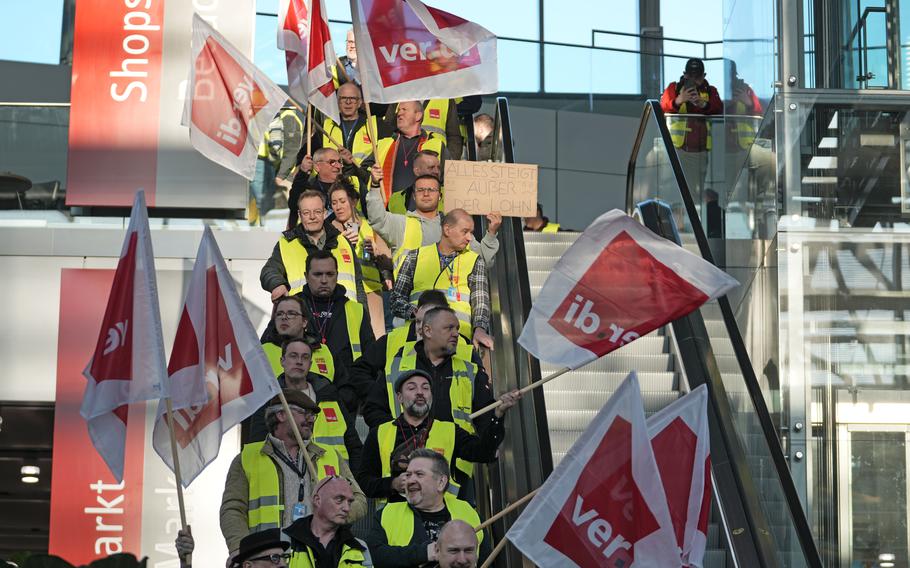 Airport workers protest wear yellow vests and hold flags during a protest.