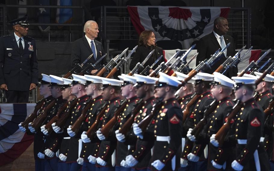 Gen. CQ Brown, from left, President Joe Biden, Vice President Kamala Harris and Defense Secretary Lloyd Austin sit on a platform behind service members at a ceremony.