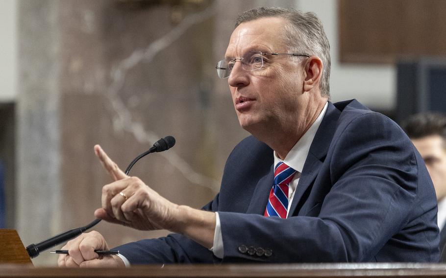 Collins is seated at a hearing, speaking and pointing his finger.