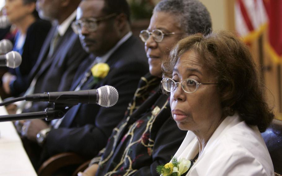 A seated woman speaks into a microphone during a conference.