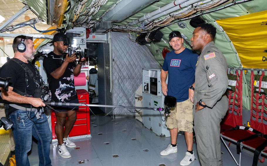 David Boreanaz talks in front of cameras aboard an aircraft.