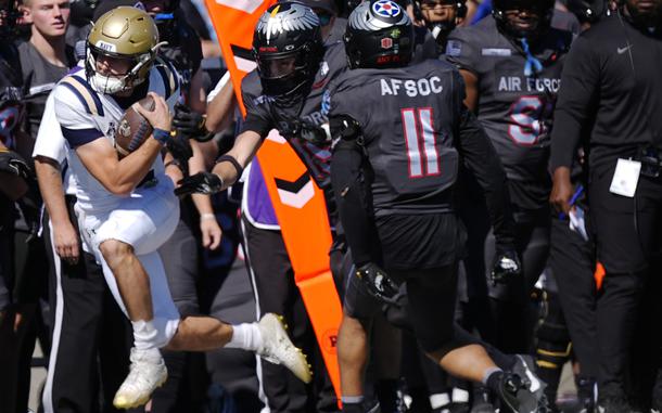 Navy quarterback Blake Horvath, left, clears the yard marker for a first down as Air Force defensive back Camby Goff, front right, and linebacker Elijah Sanders cover in the second half of an NCAA college football game Saturday, Oct. 5, 2024, at Air Force Academy, Colo.(AP Photo/David Zalubowski)