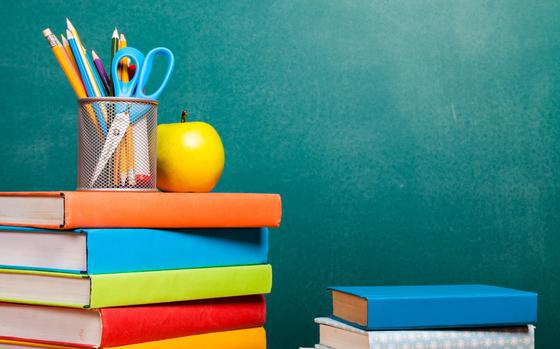 Stack of books, apple and pencils on blackboard background