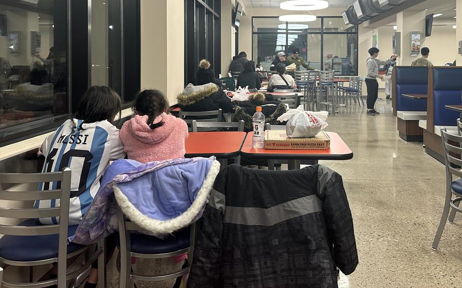 Two children sit at a table with a Pizza Hut box beside them at the renovated food court on Camp Walker. 