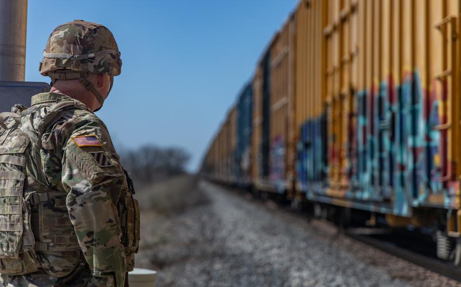 A soldier watches a train roll by.