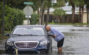 Melvin Juarbe, right, attempts to assist an unidentified driver whose car stalled in floodwaters from Hurricane Helene Thursday, Sept. 26, 2024 in Madeira Beach, Fla. The men tried to pull the car to dry land with their pickup truck but have opted to call AAA after several failed attempts. (Max Chesnes/Tampa Bay Times via AP)