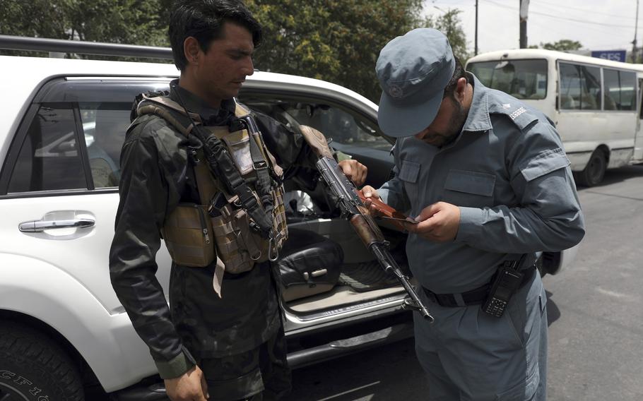 An Afghan policeman checks the documentation of a gun owner, at a temporary checkpoint in Kabul, Afghanistan, Sunday, July 4, 2021. 