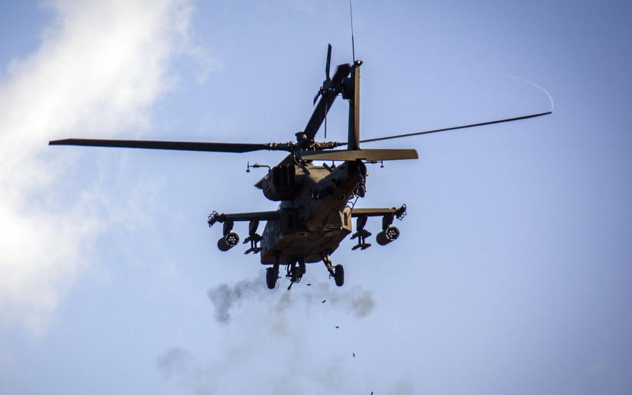 An Apache helicopter, seen from below, fires its mounted machine gun.