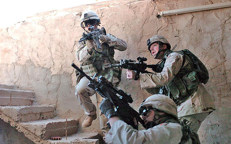 Three service in uniform climb stairs in a house in Fallujah, Iraq.