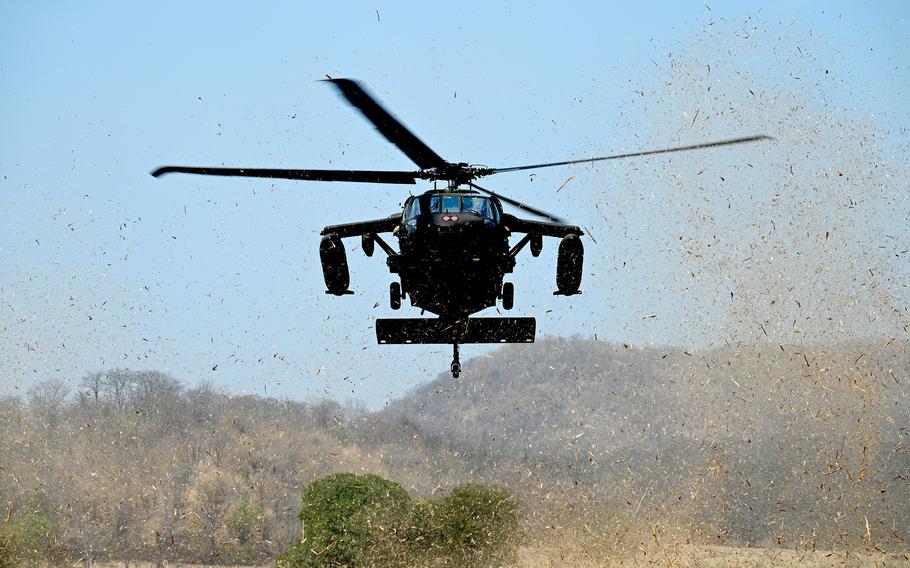 A Black Hawk kicks up debris as it lands.