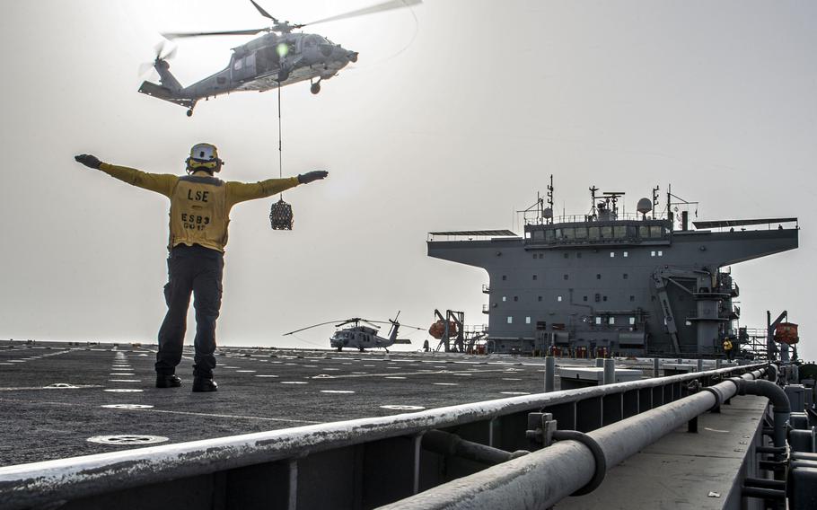 Petty officer signals to Seahawk helicopter