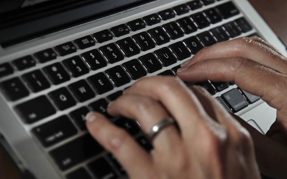 Hands type on the keyboard of a laptop computer.