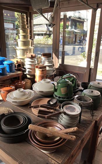 Stacks of bowls and plates are displayed on a shop counter near a window.