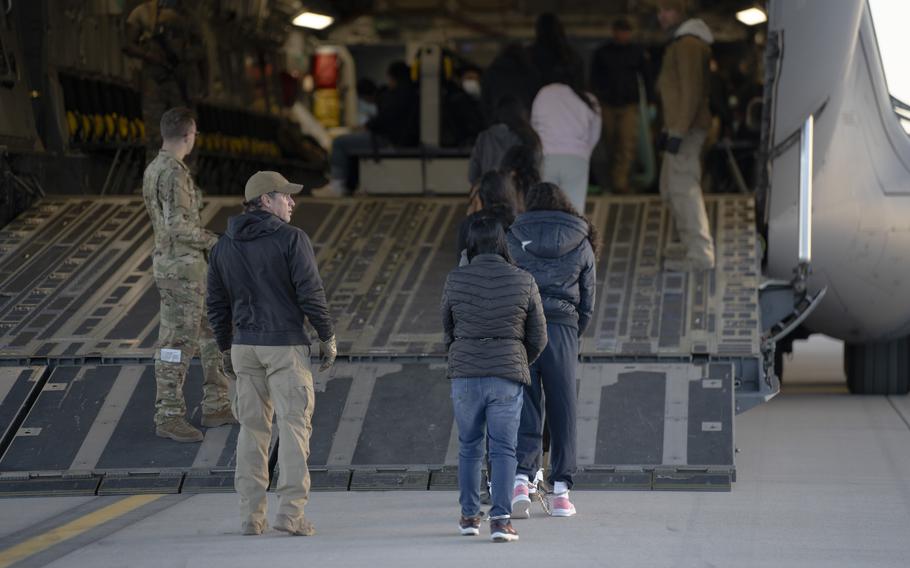 Migrants walk up the ramp into a C-17.