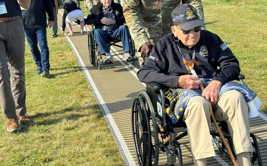 Members of a group of nearly 70 World War II veterans flown to France for the 80th anniversary of the D-Day landings head for a viewing area at Omaha Beach on June 4, 2024.