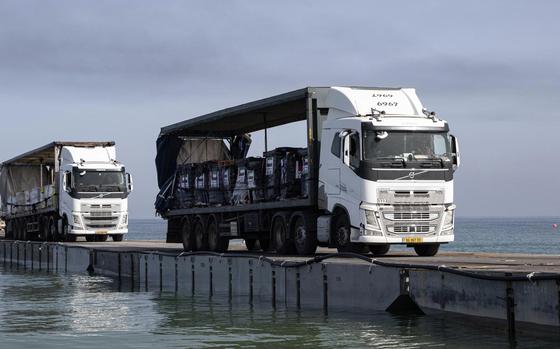 This image provided by the U.S. Army shows trucks loaded with humanitarian aid from the United Arab Emirates and the United States Agency for International Development cross the Trident Pier before arriving on the beach on the Gaza Strip, May 17, 2024. A key section of the U.S. military-built pier designed to carry badly needed aid into Gaza by boat has been reconnected to the Gaza beach following storm damage repairs and aid will begin to flow soon, the U.S. Central Command announced Friday.