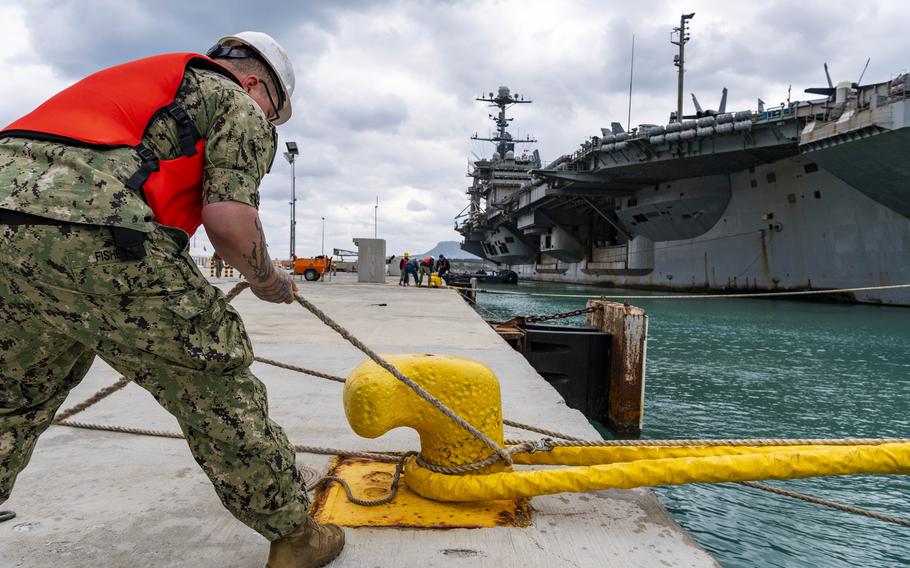 A sailor hoists the USS Truman to the dock.