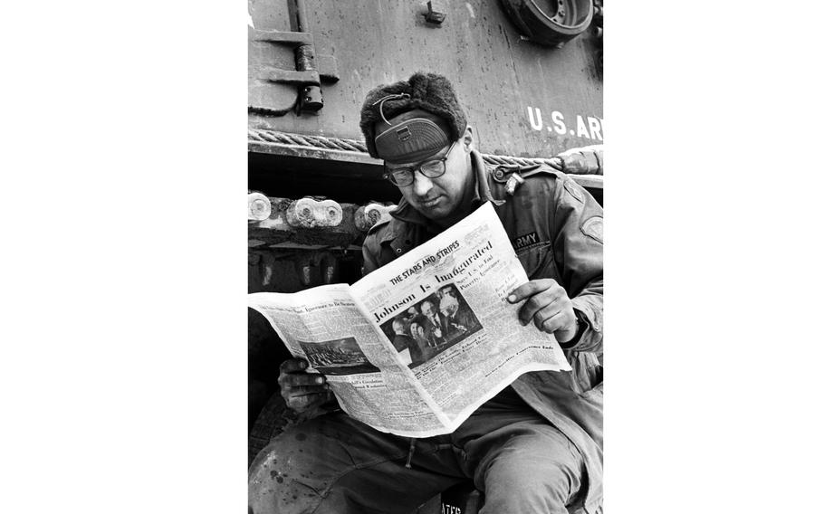 A person reading a Stars and Stripes newspaper