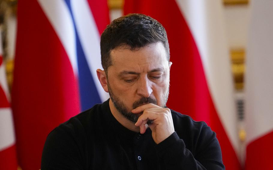 Ukrainian President Volodymyr Zelenskyy puts his hand against his chin and looks down