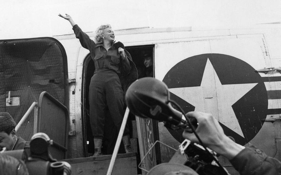 Whoops of joy filled the air as Marilyn Monroe waves an exuberant hello as she prepares to debark from the plane that carried her to Seoul