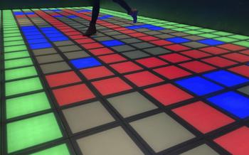 Blue, red, and green lights illuminate floor tiles in a dark room.