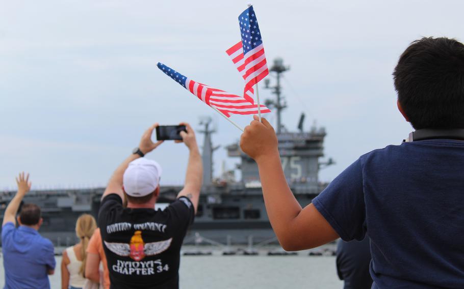 Hugo Morales waves American flags as the USS Harry S. Truman deploys