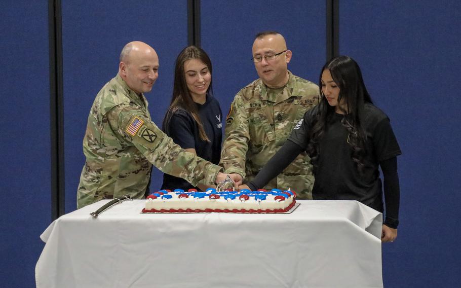 Two older members of the New York National Guard cut the cake with two younger members (one serving in the New York Air National Guard).