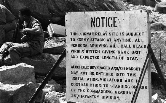 HED: Notice, 1969

A sign by one of the three helipads atop Black Virgin Mountain (Nui Ba Den) warns visitors of "enemy attack at any time." Such signs are posted at all of the helicopter landing pads, instructing visitors to give name, unit, address of next-of-kin to Black Virgin Mountain's switchboard so your kin can be notified if you get blown away during the night. Mortar attacks by the Viet Cong who occupy positions down the mountain and in the flatlands below is an almost nightly occurrence for the outpost.

Read more about life in the camp above the clouds and see additional photos here.
https://www.stripes.com/history/1969-10-24/black-virgin-mountain:-nice-place-%E2%80%94-to-visit-1826470.html

META TAGS: Vietnam War; camp; base; U.S. Army; sign; warning; 