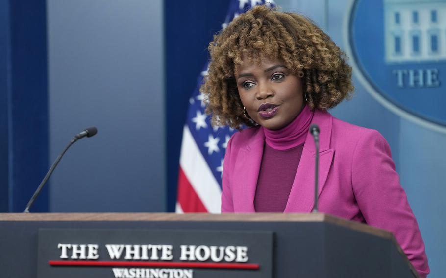 White House press secretary Karine Jean-Pierre in a pink suit at a podium that reads “The White House.”