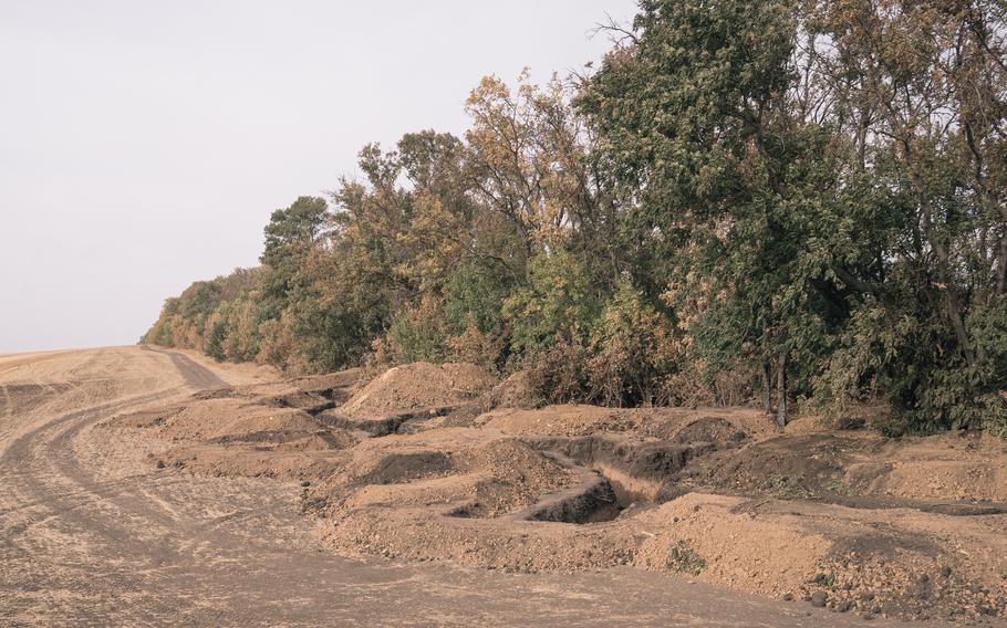 A trench and mounds of dirt along a tree line in the Donetsk region of Ukraine.