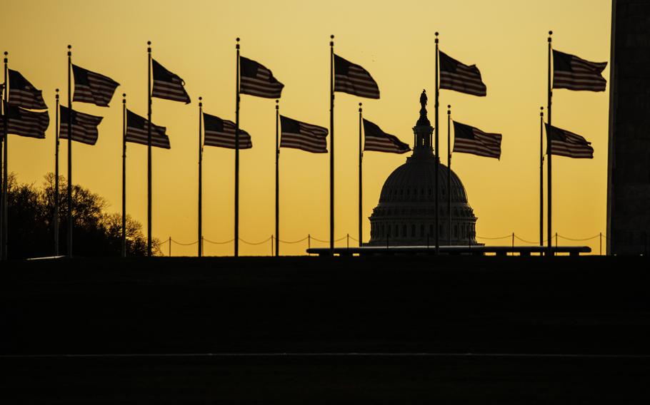The U.S. Capitol dome is seen past the base of the Washington Monument as the sun rises on Nov. 9, 2022, in Washington.