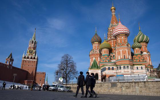 Three police officers walk in Moscow’s Red Square on a sunny day.