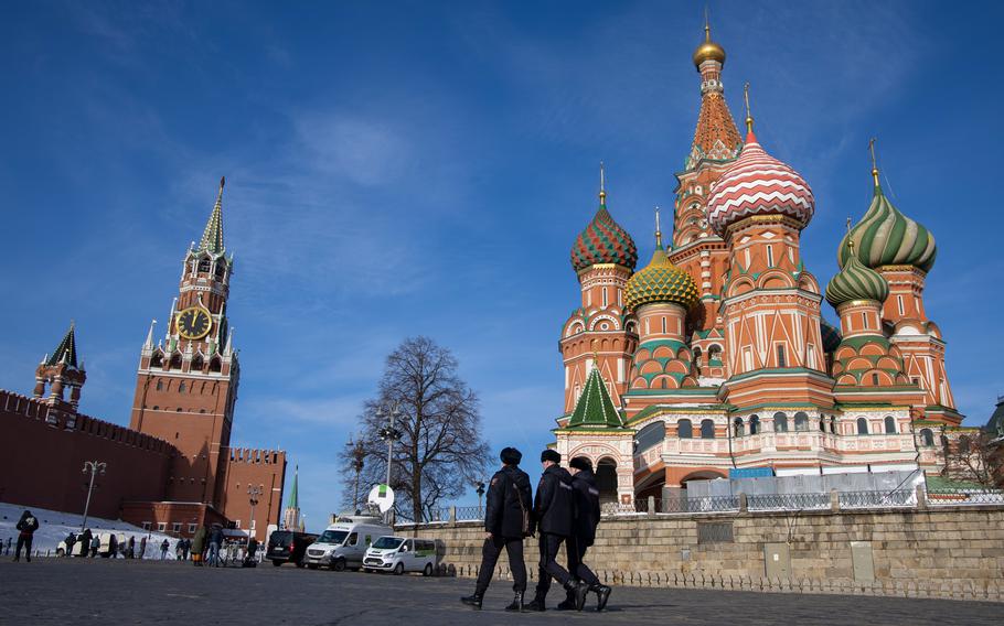 Three police officers walk in Moscow’s Red Square on a sunny day.