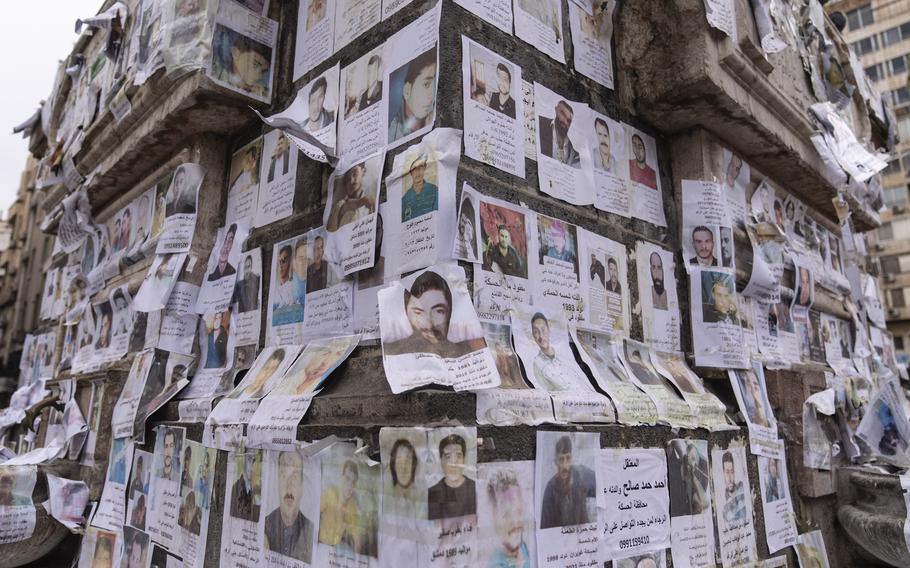 A wall is covered with posters showing faces and names of missing people.